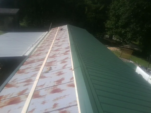 Old rusted panels beside newly installed green metal roofing — Wind Damage Roof Repair by Roofing Brothers in Estillfork