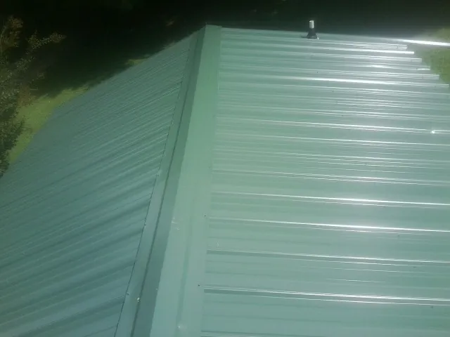 New green metal panels meeting at the ridge of a roof — Flat Roof Repair work by our crew in Estillfork