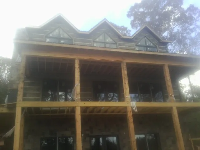 Dormers and porch framing on a large log home under construction — Roof Coating work by our crew in Estillfork