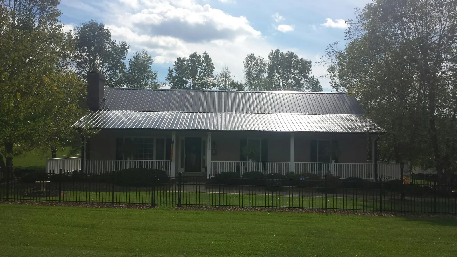 Gray metal roof on a brick ranch with a full width front porch — Gutter Guard Installation work by our crew in Estillfork
